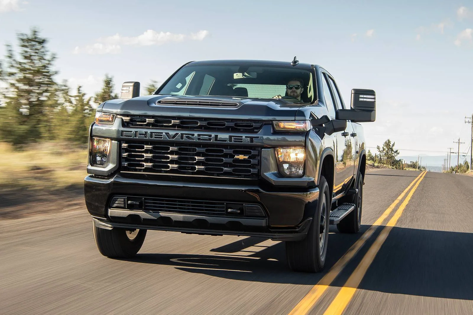 Black 2020 Chevrolet Silverado 2500HD heavy-duty pickup truck driving on highway with motion blur