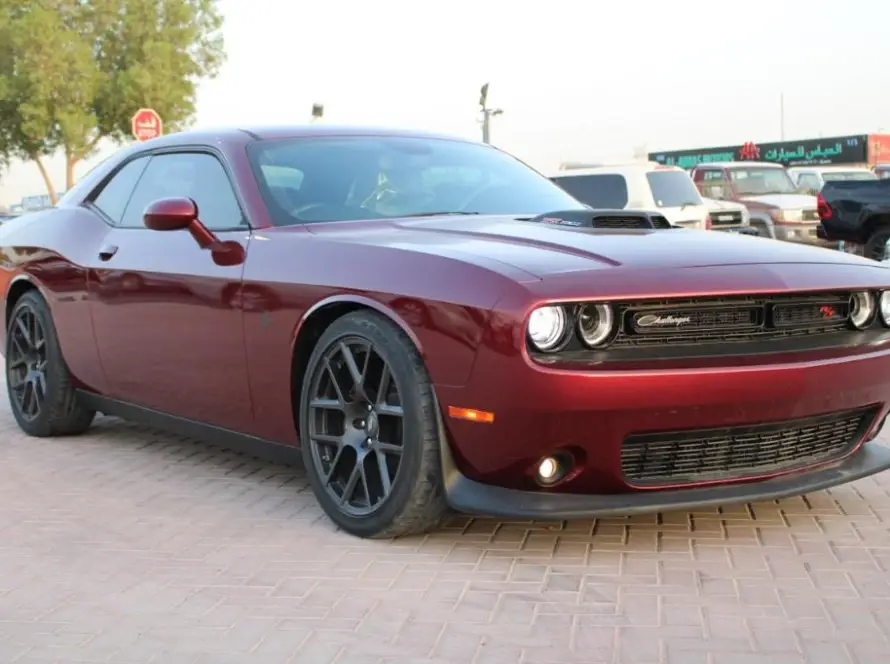 Dark red Dodge Challenger muscle car parked on brick paving with LED headlights and body kit