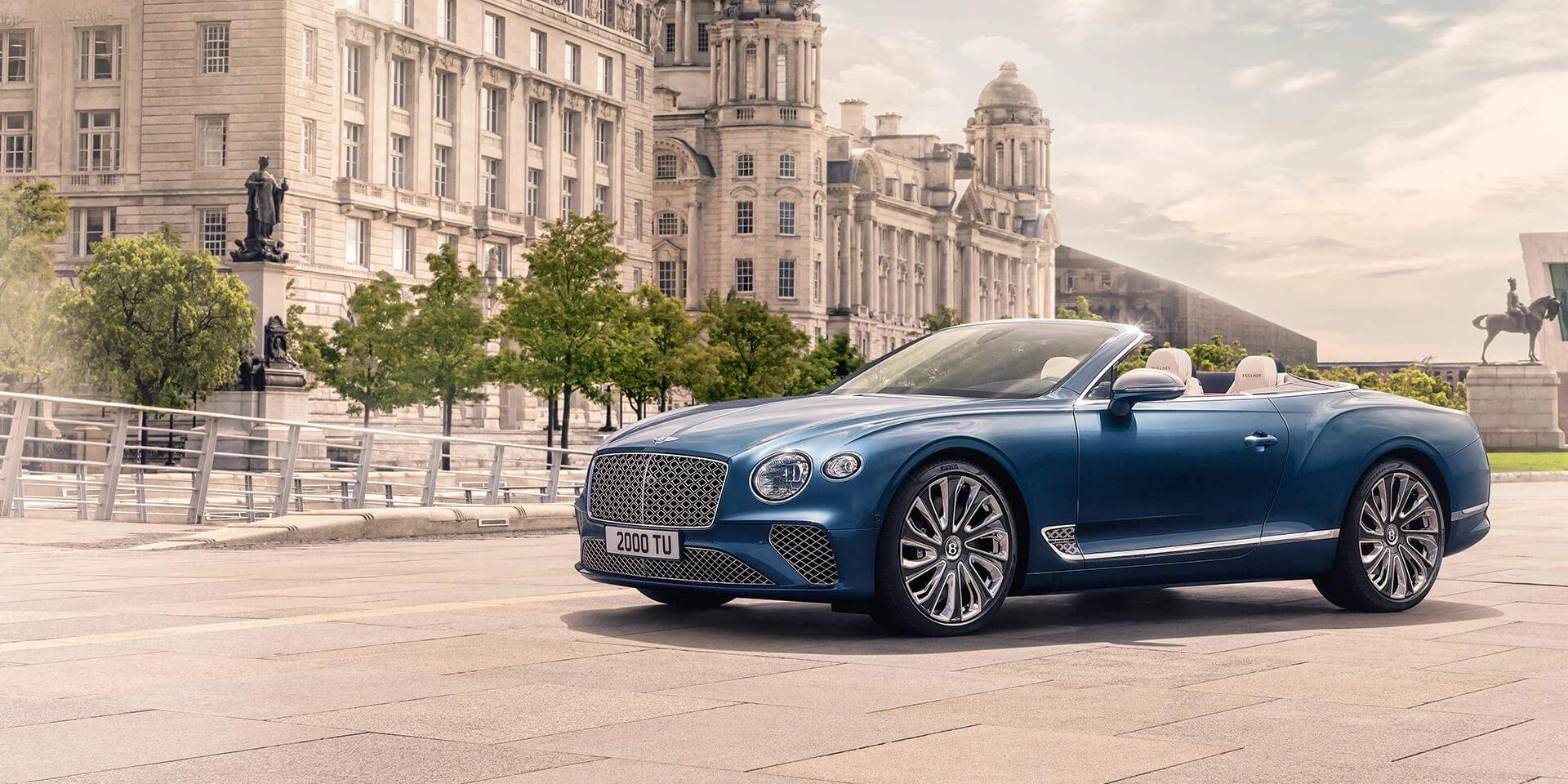 Blue Bentley Continental GTC Mulliner luxury convertible in elegant European city square with classical architecture