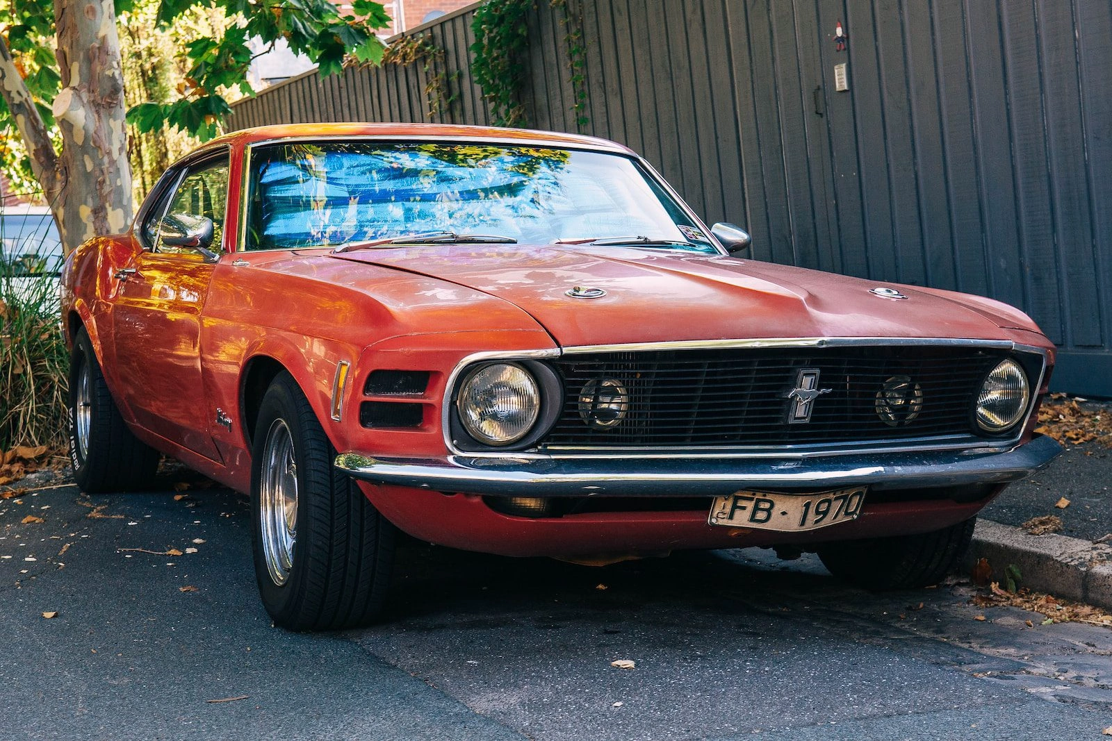 Classic orange red Ford Mustang vintage muscle car parked in front of gray corrugated metal building