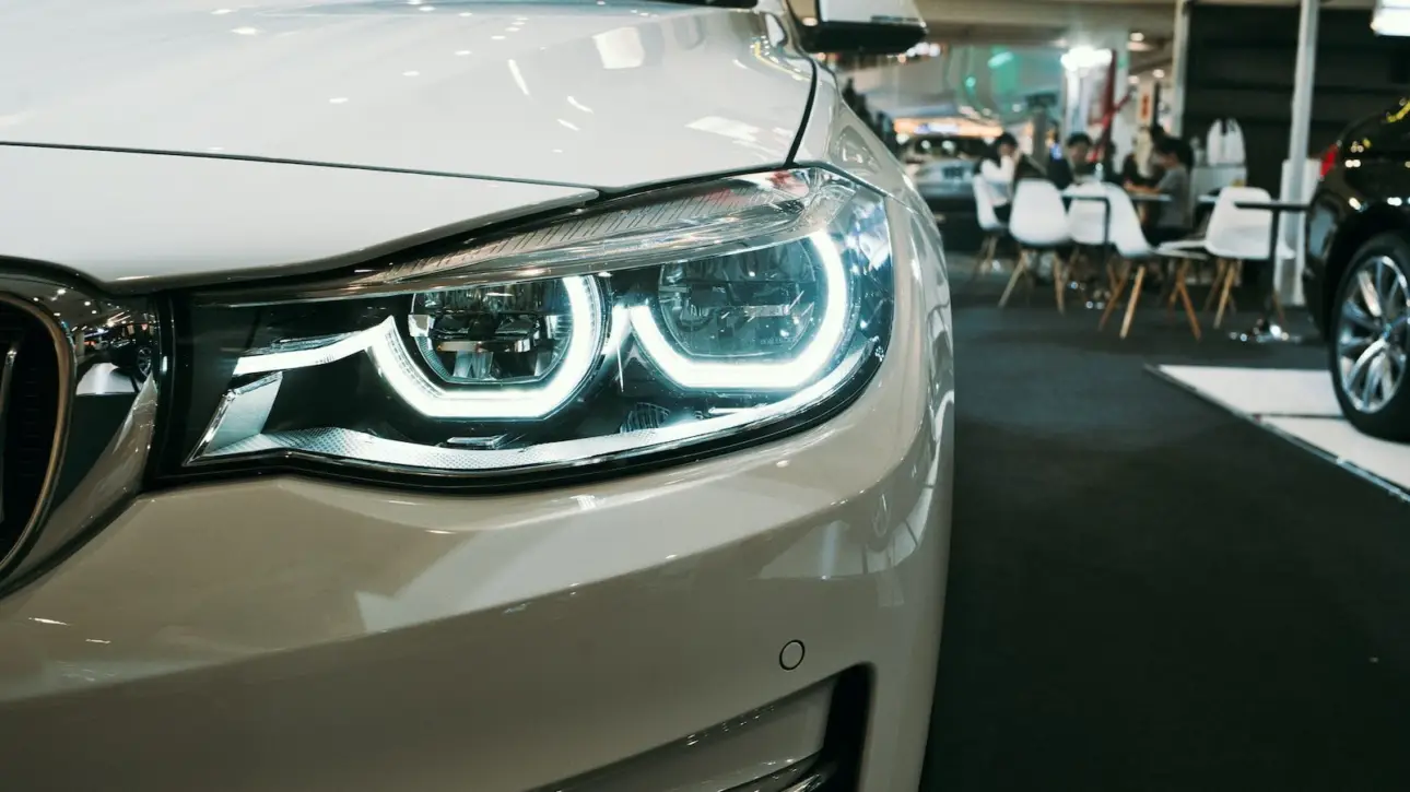 Close-up of white BMW luxury sedan LED headlights and front grille in showroom