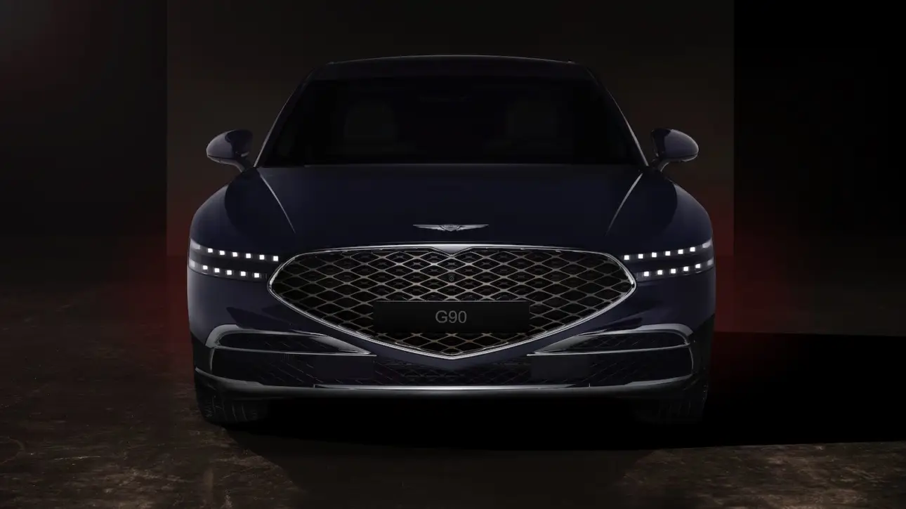 Genesis luxury sedan front view with diamond-pattern grille and LED headlights in dramatic dark studio lighting
