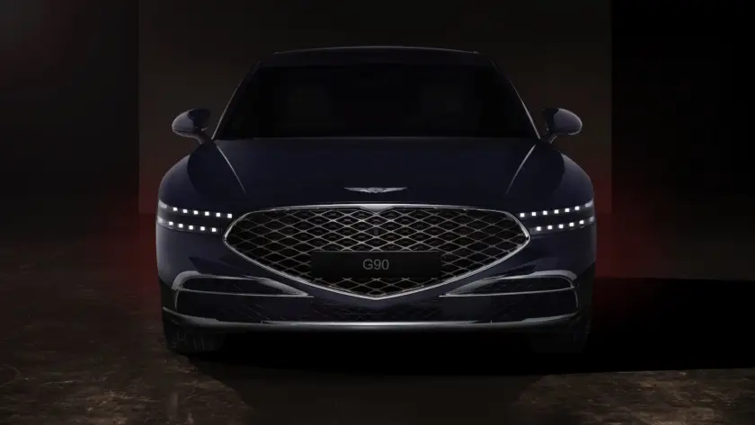 Genesis luxury sedan front view with diamond-pattern grille and LED headlights in dramatic dark studio lighting