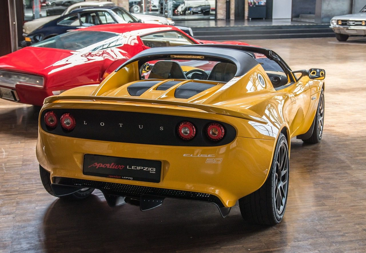 Yellow Lotus Elise convertible sports car rear view in luxury showroom with classic cars