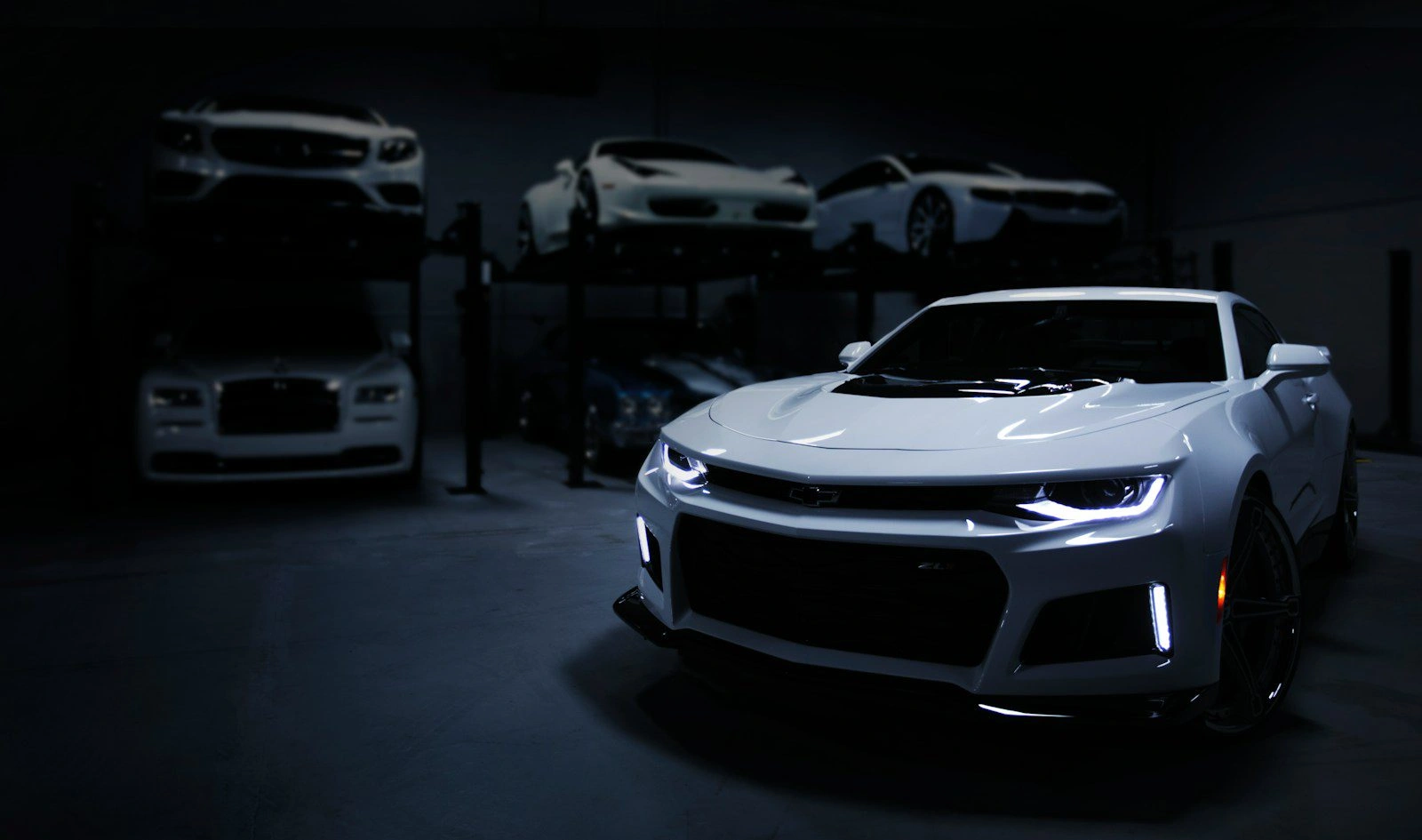 White Chevrolet Camaro ZL1 muscle car with LED headlights in dramatic dark showroom lighting