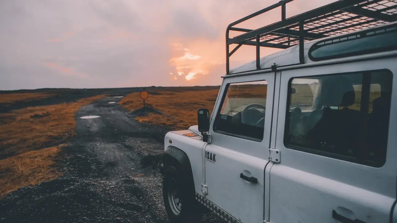 White Ineos Grenadier SUV with roof rack at sunset off-road location showcasing luxury adventure vehicle