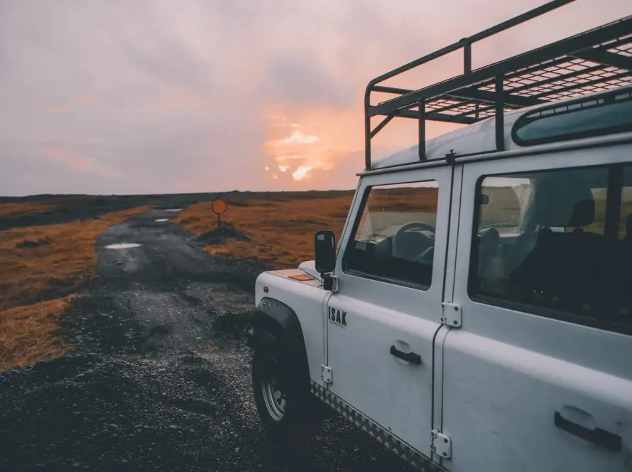 White Ineos Grenadier SUV with roof rack at sunset off-road location showcasing luxury adventure vehicle