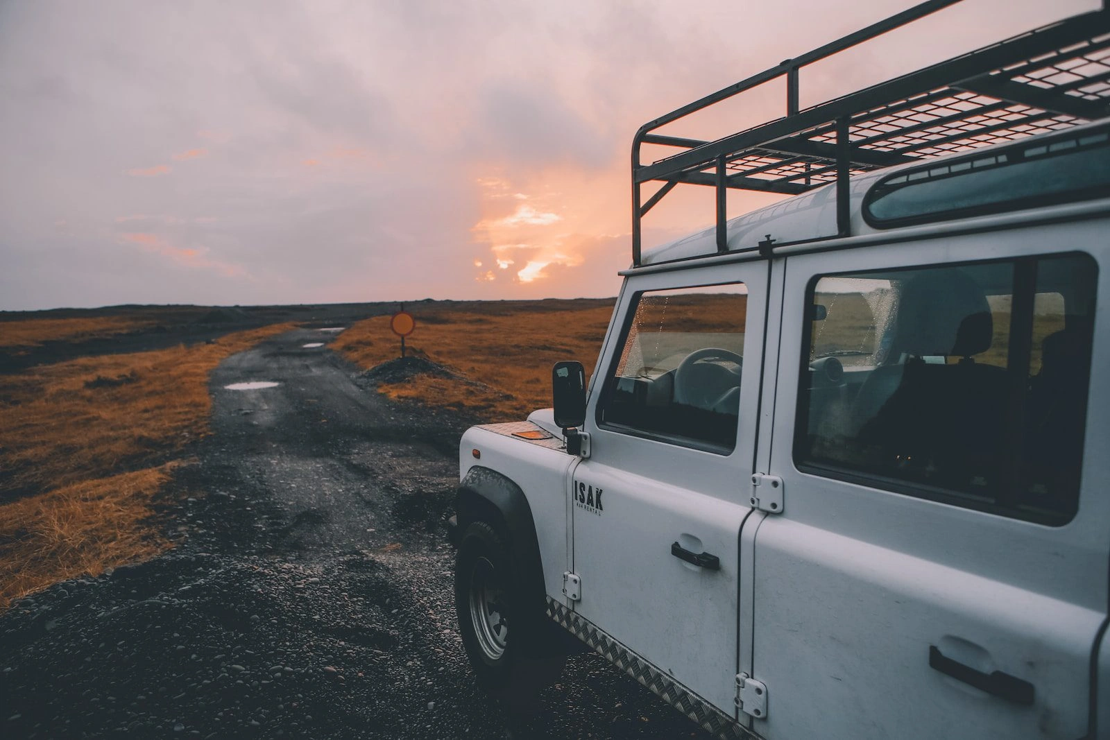 White Ineos Grenadier SUV with roof rack at sunset off-road location showcasing luxury adventure vehicle