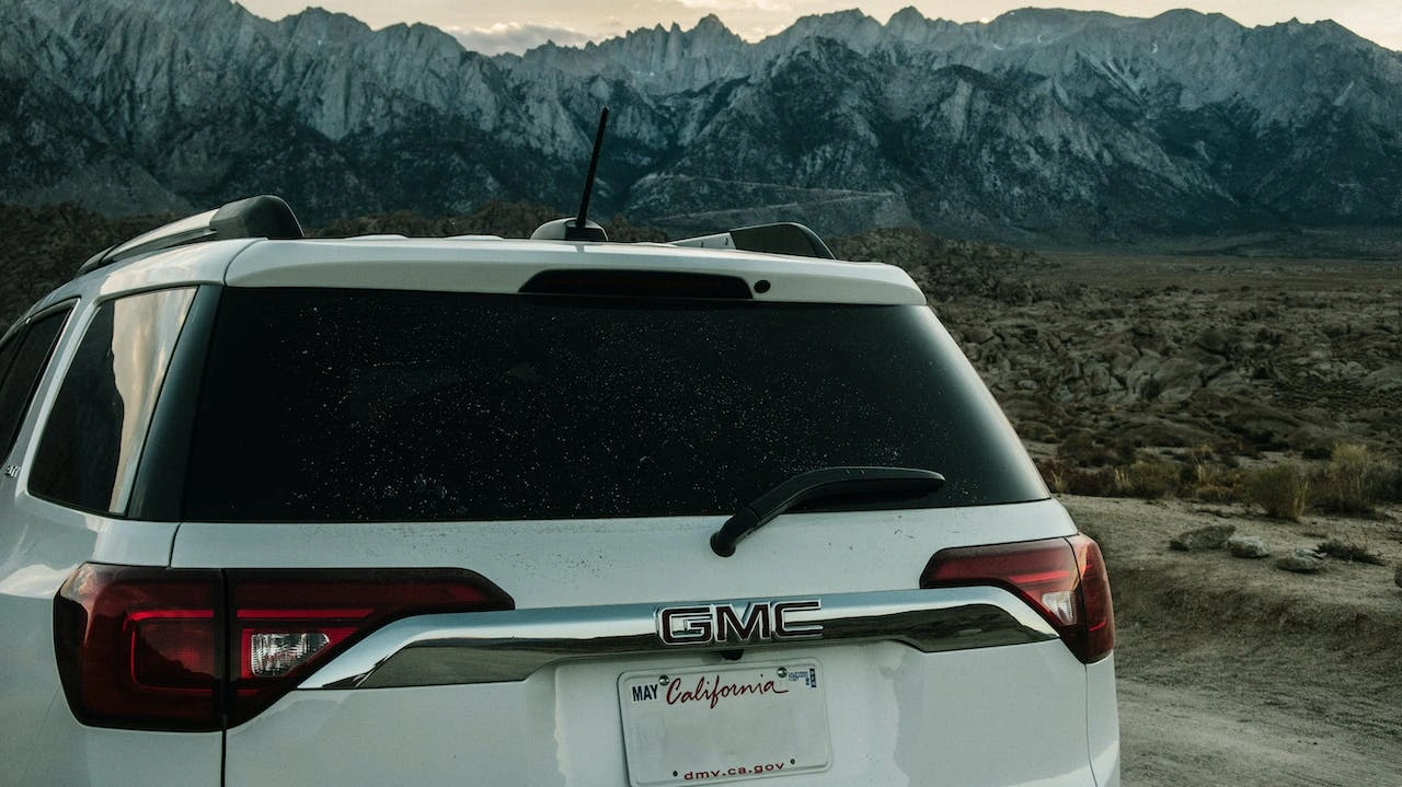 White GMC Yukon SUV rear view with mountain landscape exploring imported cars availability in India
