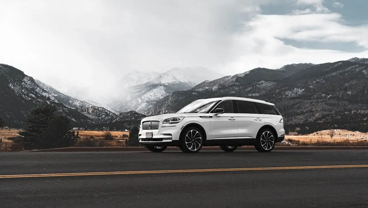 White Lincoln Navigator luxury SUV on mountain highway showcasing reliability of best muscle cars in India