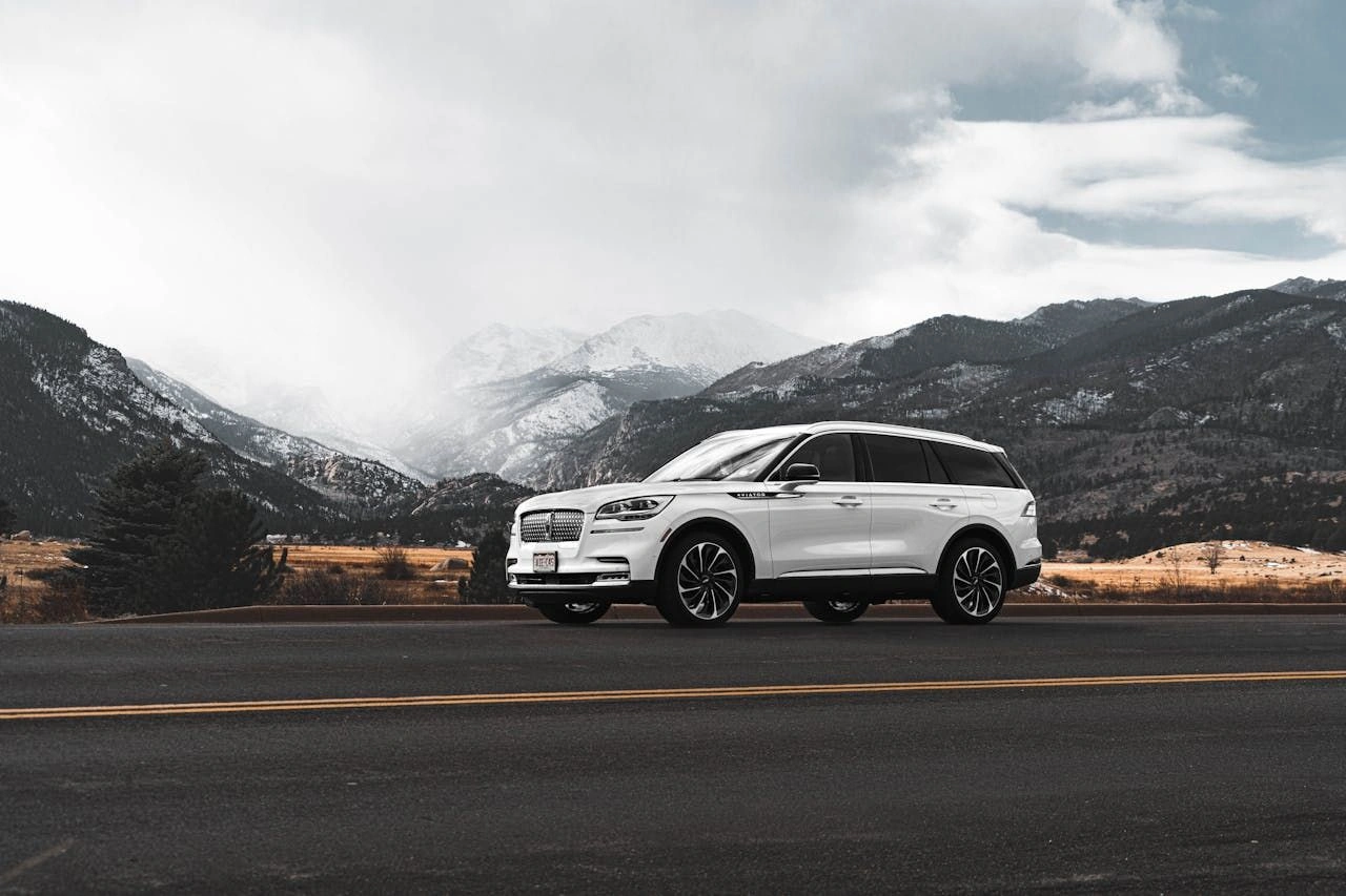 White Lincoln Navigator luxury SUV on mountain highway showcasing reliability of best muscle cars in India