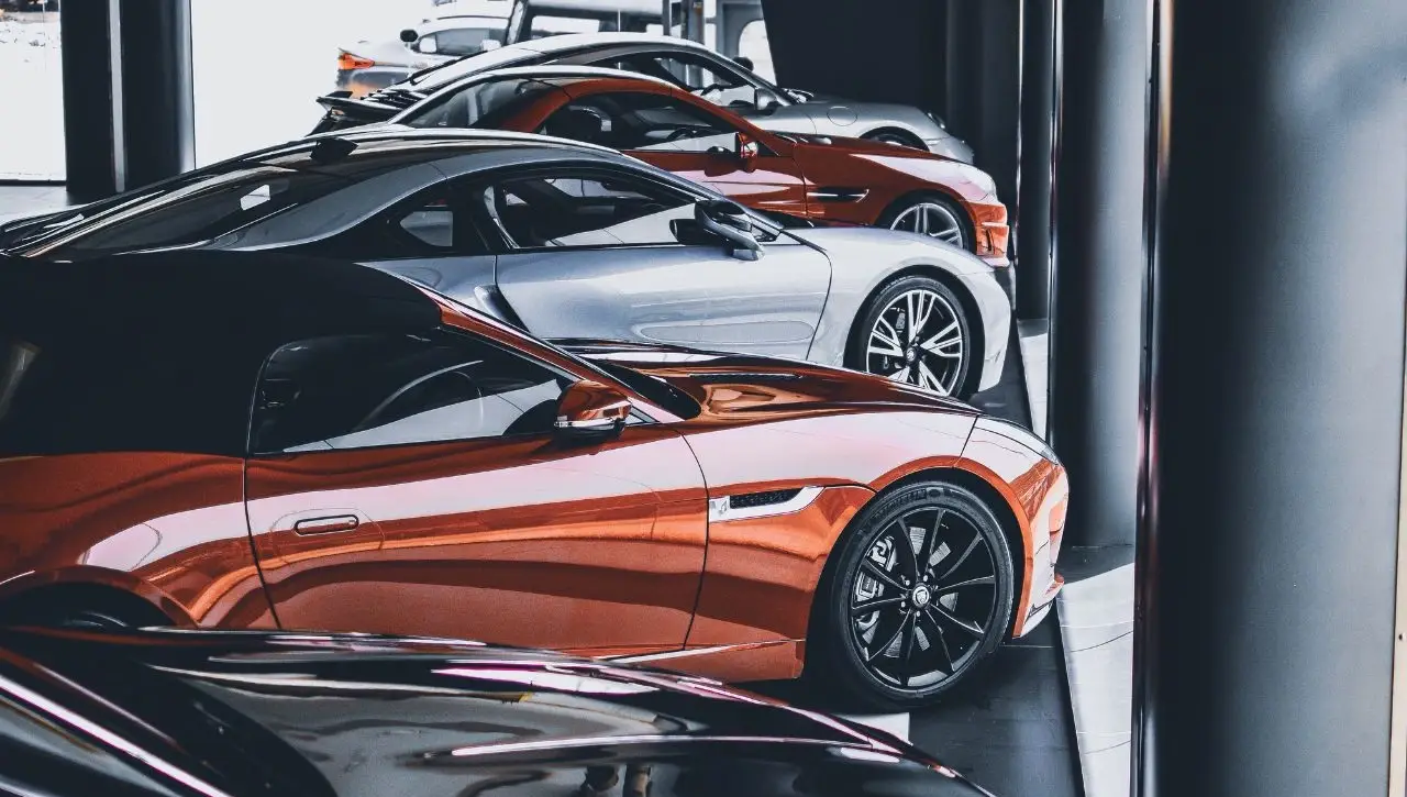 Multiple exotic sports cars in luxury showroom including orange and silver supercars explaining how to import vehicles to India