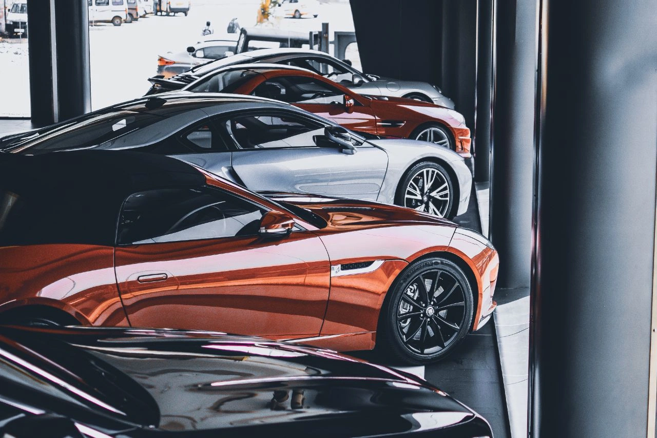 Multiple exotic sports cars in luxury showroom including orange and silver supercars explaining how to import vehicles to India