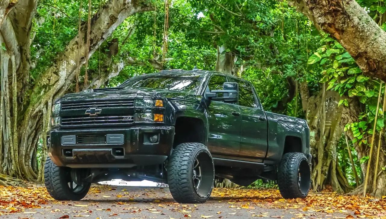 Black Chevrolet Silverado pickup truck in forest autumn setting exploring evolution of pickup trucks global appeal