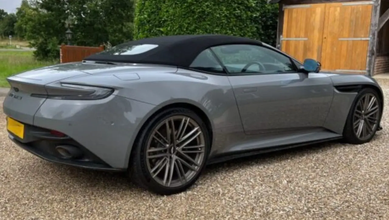 Grey Aston Martin DB12 convertible sports car parked on gravel drive exploring how fast this luxury icon goes