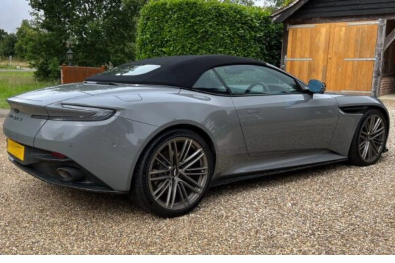Grey Aston Martin DB12 convertible sports car parked on gravel drive exploring how fast this luxury icon goes