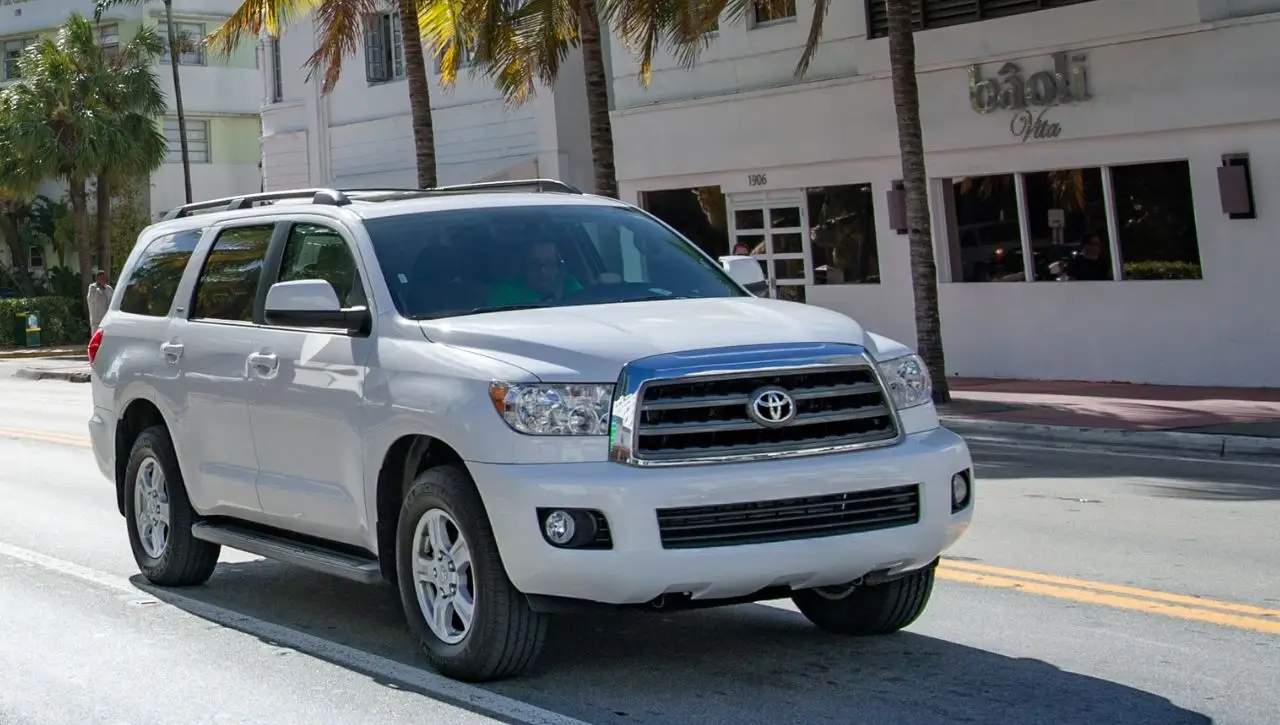 White Toyota Land Cruiser SUV parked on street with palm trees in background