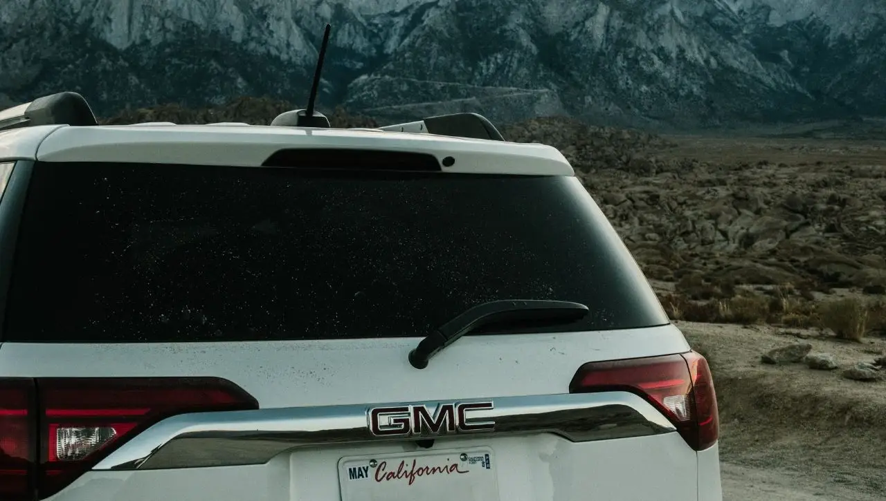 White GMC Hummer EV electric SUV parked in desert landscape with mountain range in background