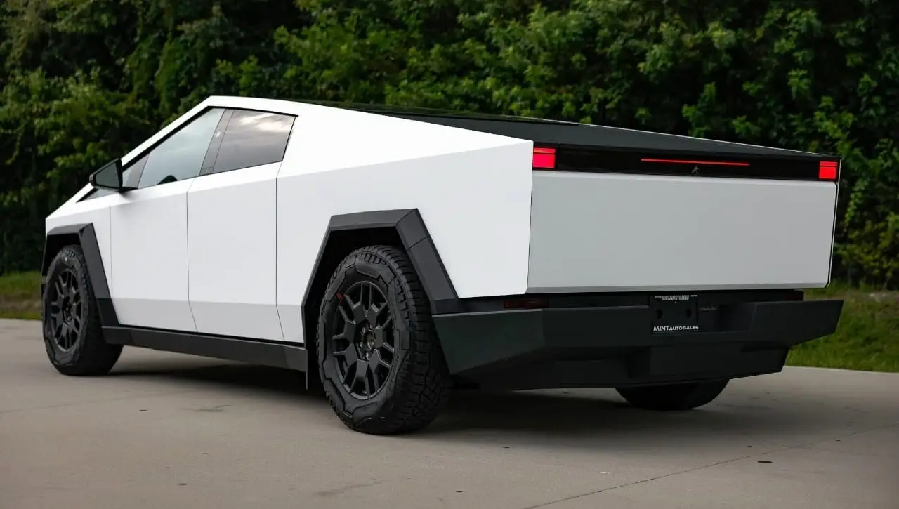 Tesla Cybertruck rear view showing white angular exterior with black bed and red taillights on asphalt driveway