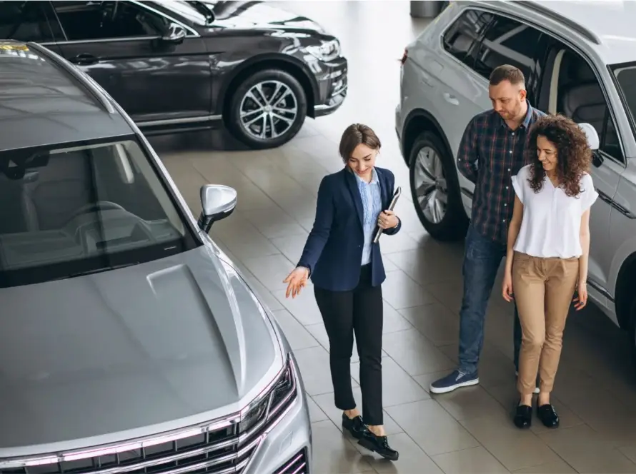 Three people at luxury car showroom discussing top 5 most sought-after imported luxury cars in India