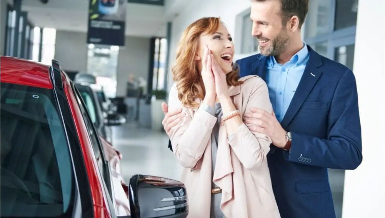 Happy couple at car dealership celebrating purchase guide to buying luxury cars in India with everything you need to know