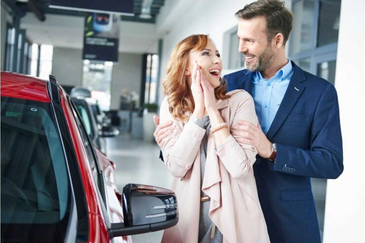 Happy couple at car dealership celebrating purchase guide to buying luxury cars in India with everything you need to know