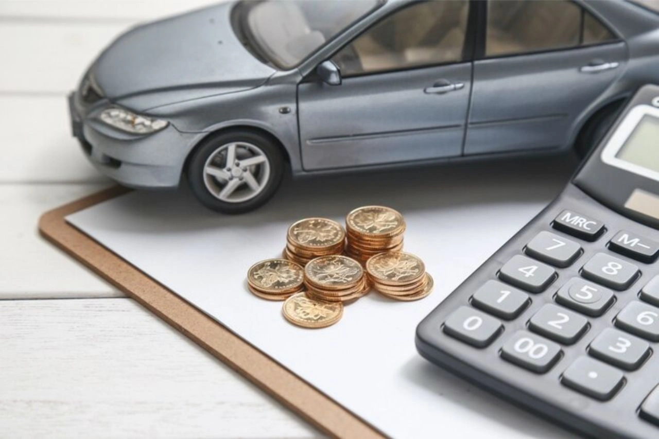 Calculator and coins with car model illustrating luxury car taxes in India and how much it really costs