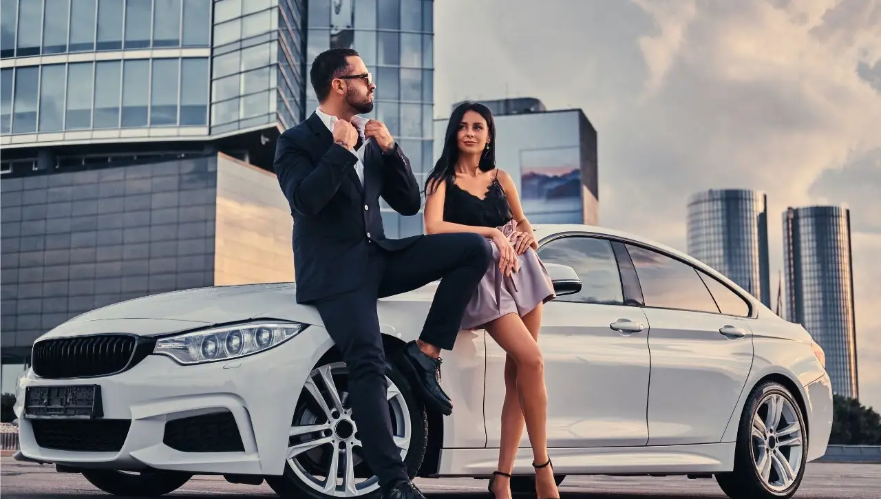 Elegant couple beside white BMW European luxury car on city rooftop class apart from ordinary vehicles in India