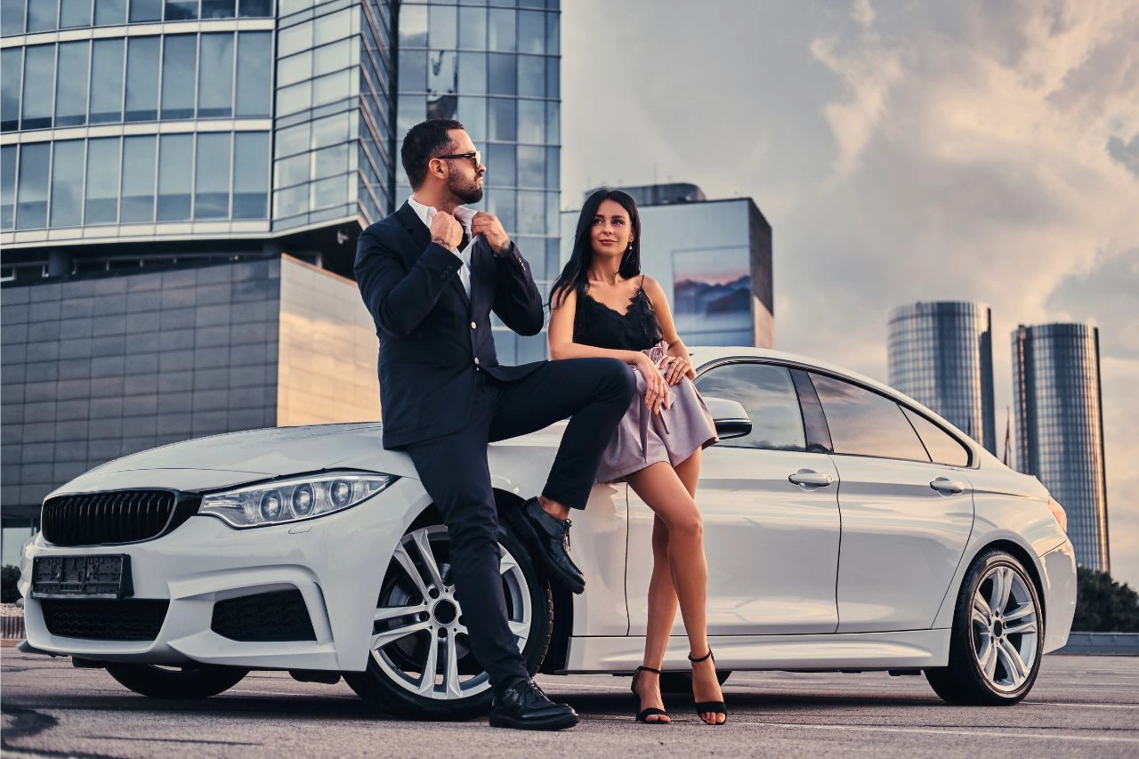 Elegant couple beside white BMW European luxury car on city rooftop class apart from ordinary vehicles in India