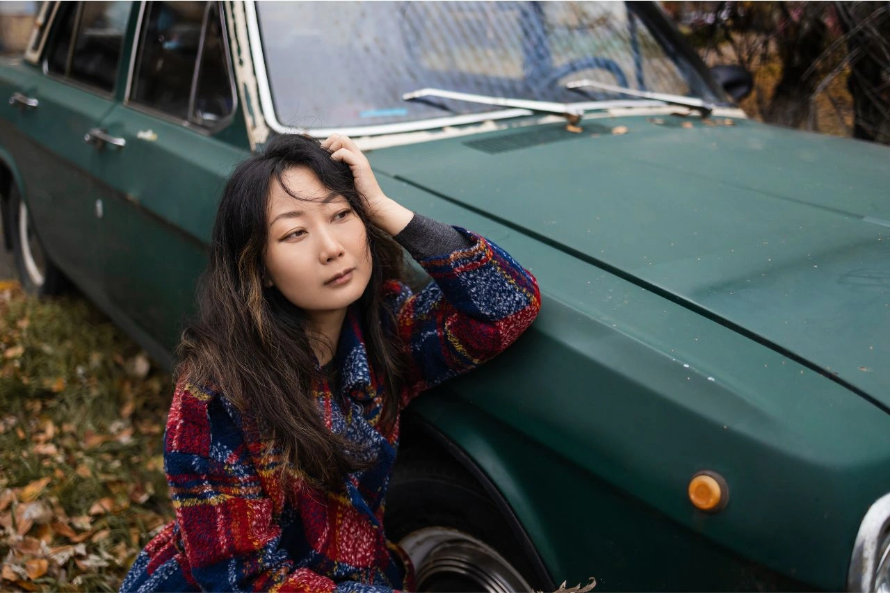 Woman sitting beside vintage green Japanese classic car timeless icon that still turns heads today
