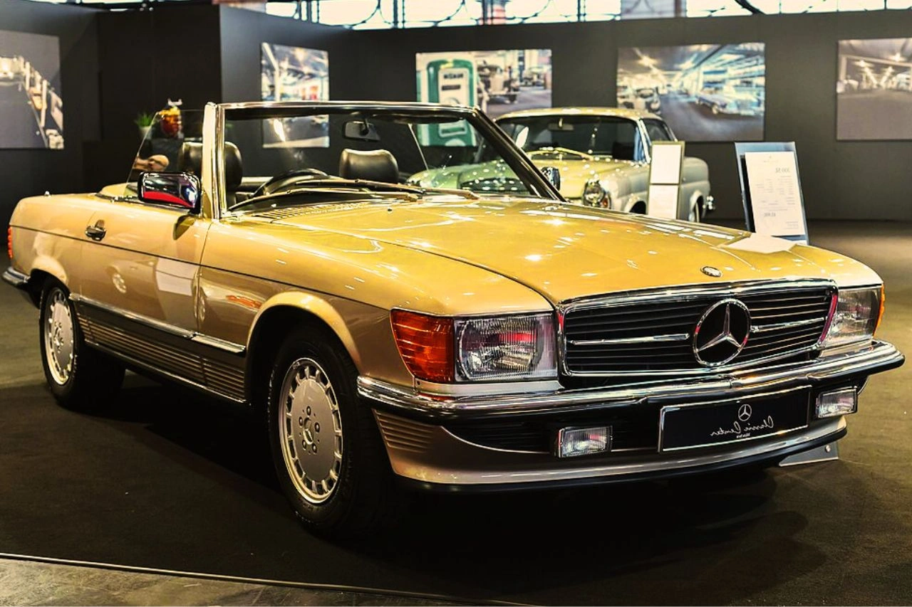Gold Mercedes-Benz SL R107 convertible in showroom timeless style why 1971-1975 model is worth so much more today