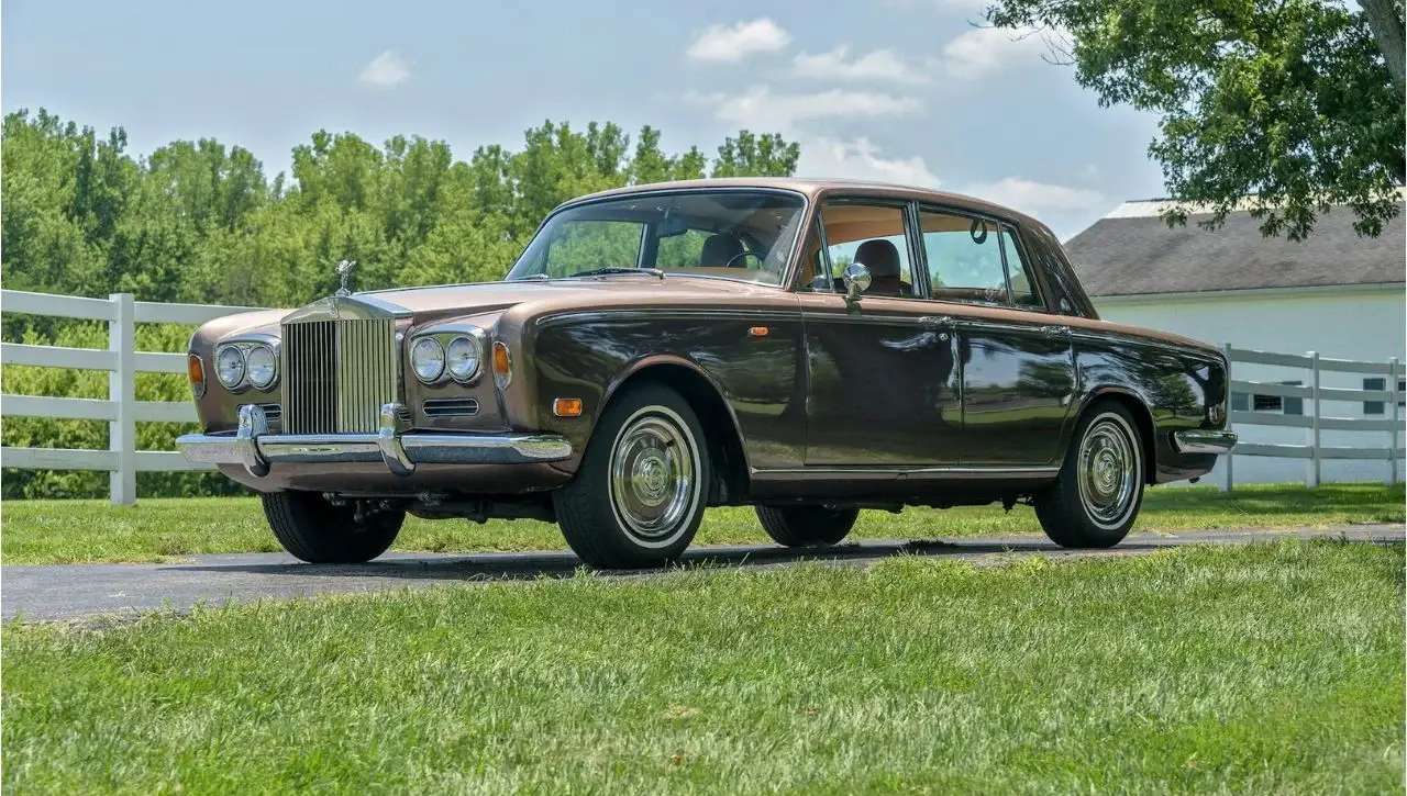 Classic dark green Rolls-Royce Silver Shadow II luxury sedan from 1970s on grass field